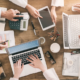 A group of professionals working on laptops and tablets, discussing data protection in New York, cybersecurity strategies, and secure business operations.