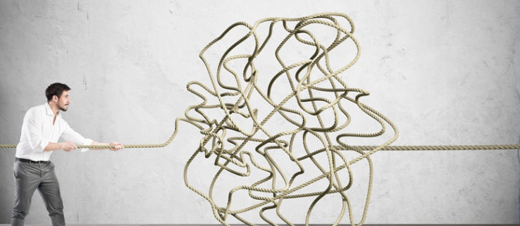 A businessman pulling a tangled rope, symbolizing the complexity of data security in New York, cybersecurity challenges, and compliance regulations.