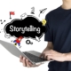 Person using a laptop with creative icons and the word "Storytelling" displayed, representing how managed IT services in New York support immersive digital content creation and seamless storytelling experiences.