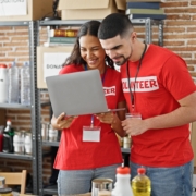 Two volunteers in a donation center smiling at a laptop, illustrating how nonprofits benefit from managed IT services in New York City to stay connected, efficient, and secure.