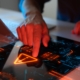 Close-up of a person's hand interacting with a futuristic touchscreen interface displaying a warning symbol and digital data, symbolizing threat detection and system monitoring — representing advanced cyber risk management in New York.